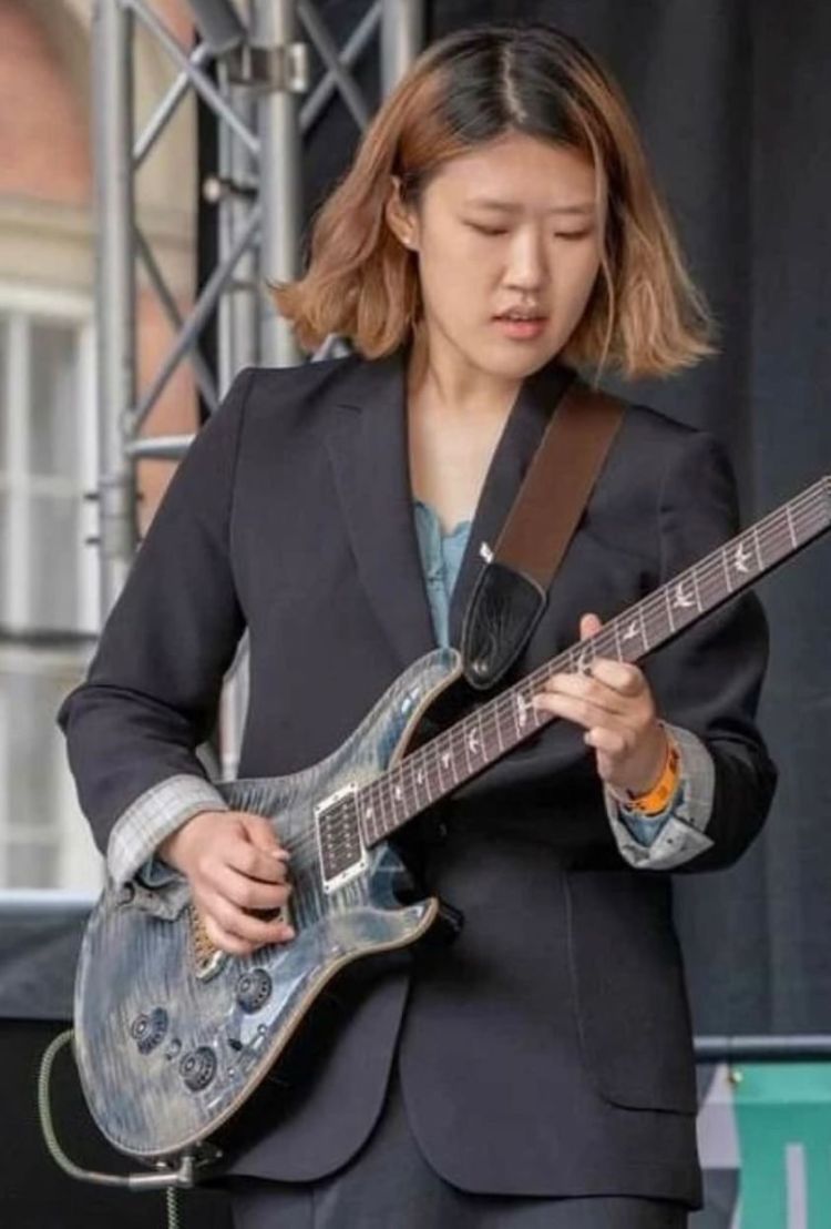Hyo Jung playing an electric guitar on stage